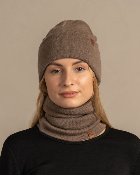 Woman wearing knitted merino wool beanie and gaiter in brown color.
