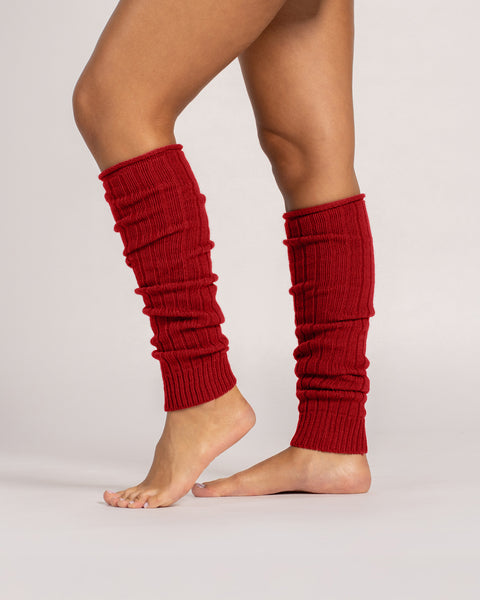 Close-up of red ribbed wool leg warmers worn barefoot, showing soft knit texture and slouchy fit.