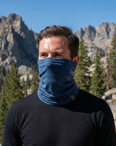 Man wearing denim blue merino wool long neck gaiter in mountain setting, breathable temperature-regulating face and neck protection for hiking