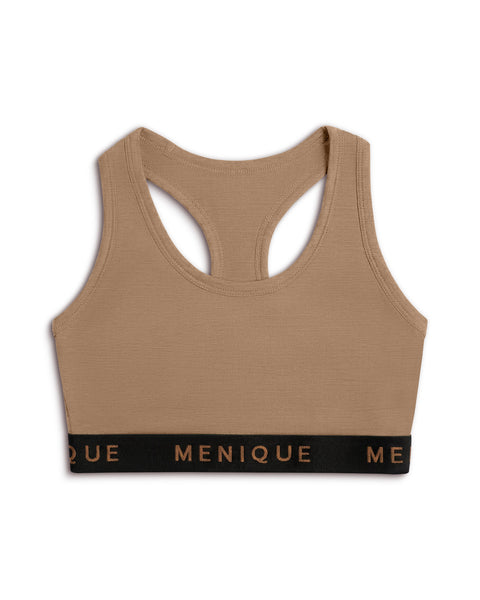 A product shot of a beige racerback sports bra laid flat against a plain white background. The bra features a wide black elastic underbust band with the brand name "MENIQUE" printed across the front in bronze lettering.