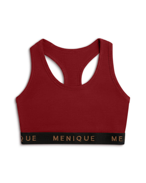 A product shot of a deep red (royal cherry) racerback sports bra laid flat against a plain white background. The bra features a wide black elastic underbust band with the brand name "MENIQUE" printed across the front in bronze lettering.