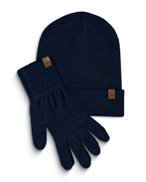 A blue knitted beanie and a pair of matching gloves are laid flat against a white background. Both the beanie and each glove have a small, rectangular brown leather tag with a menique logo on them. The items are slightly overlapping, with the beanie positioned above and to the left of the gloves.