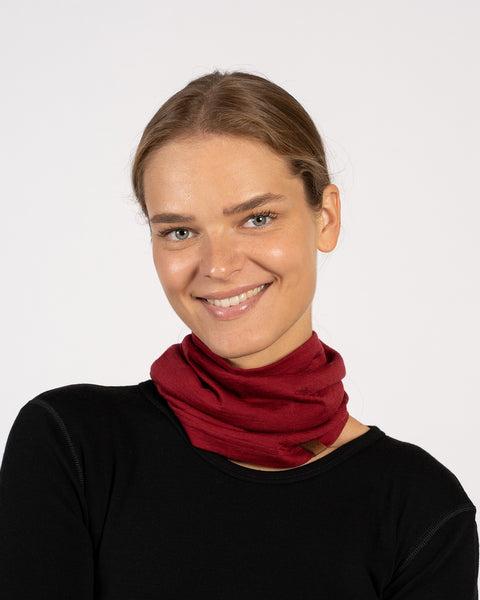 Smiling woman wearing a royal cherry red Merino wool neck gaiter as a neck warmer, paired with a black top.