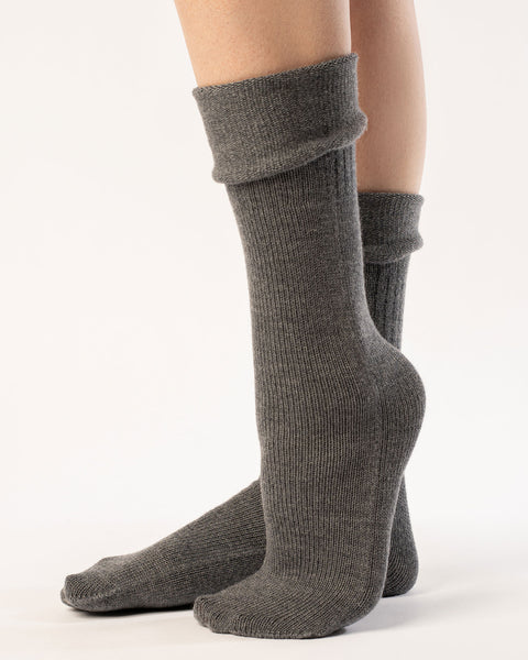 A woman wearing long merino wool socks in dark gray color.
