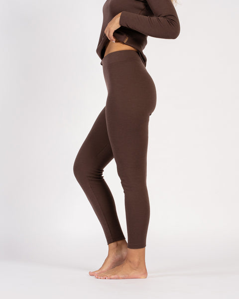 Side profile of woman in brown merino wool leggings and long-sleeve top.