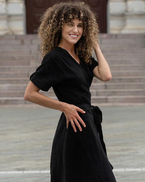 Woman outside in the city posing with a pure black linen dress eliana.
