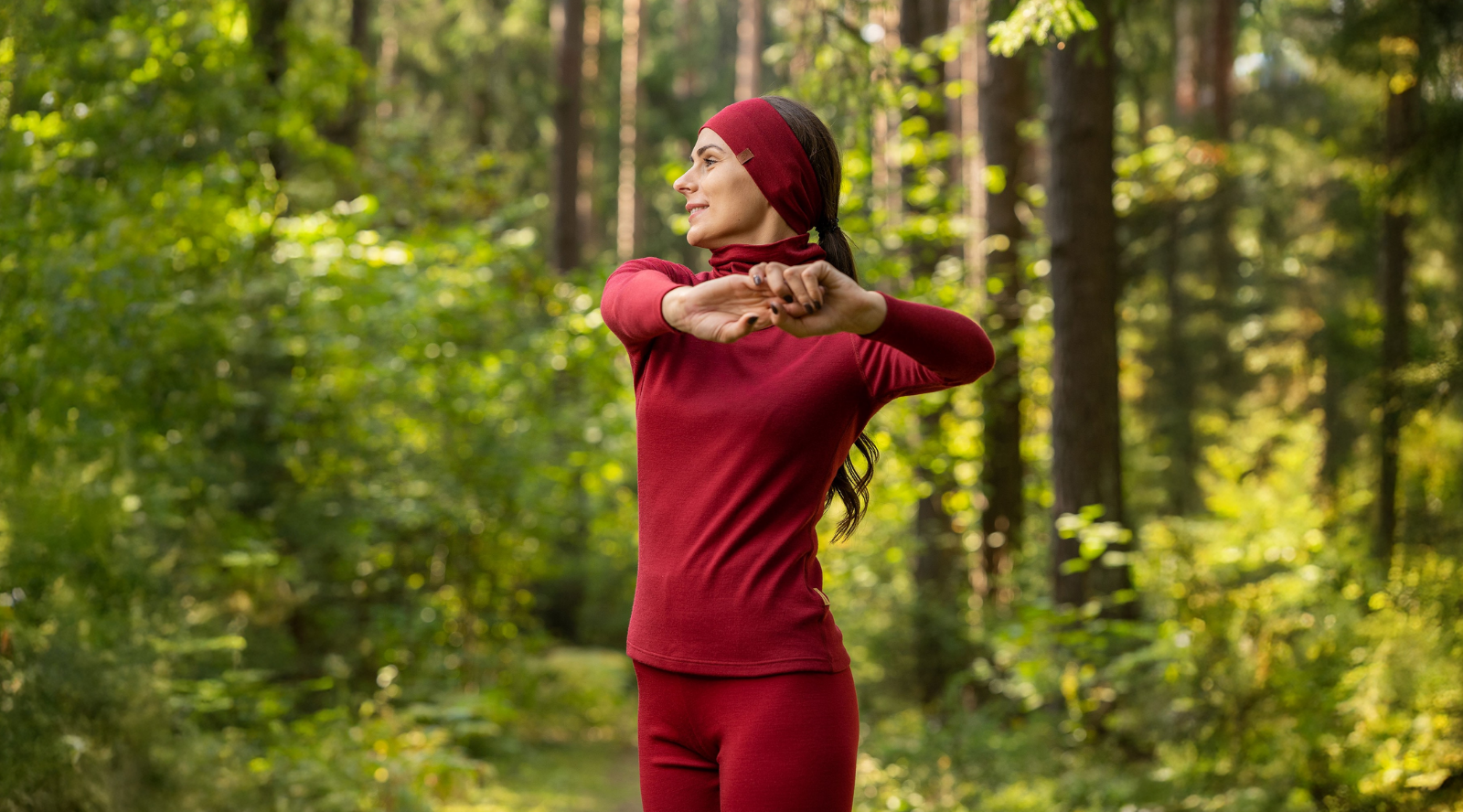 In the photo you can see woman standing, behind her there are exercising tools, such as weights. The woman is wearing black tank top with leggings made from organic 100% Merino Wool.