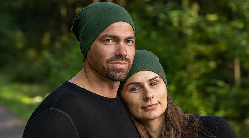 In the photo you can see couple standing closely. They are both wearing bright and dark green color slouchy beanie hats and smiling.
