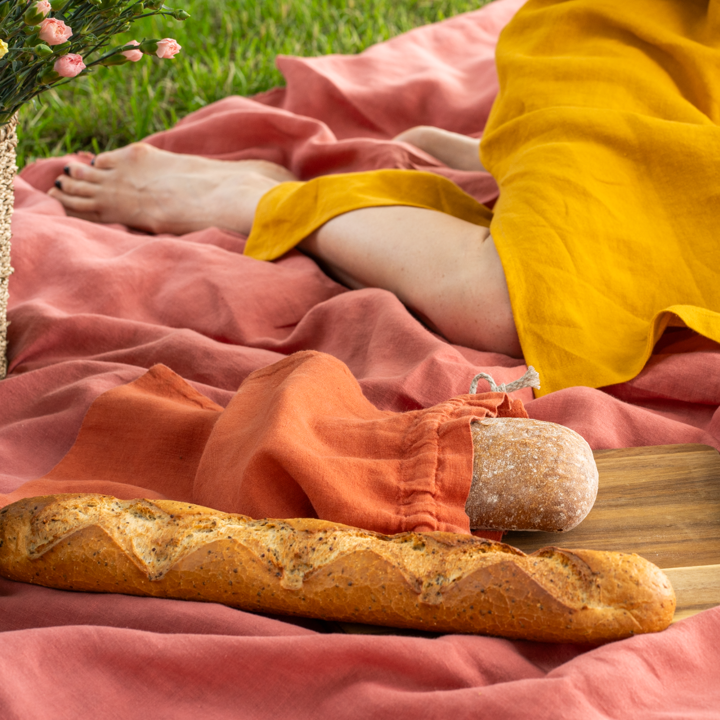 Reusable Linen Bread & Baguette Bag in Cinnamon Red color on a blanket and a wooden board.