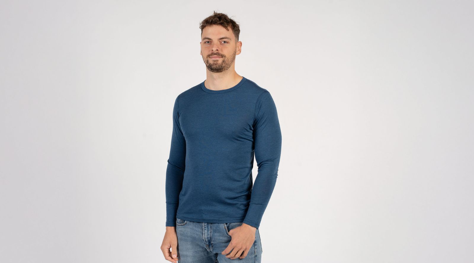 Man wearing a blue long-sleeve shirt and jeans on a white background