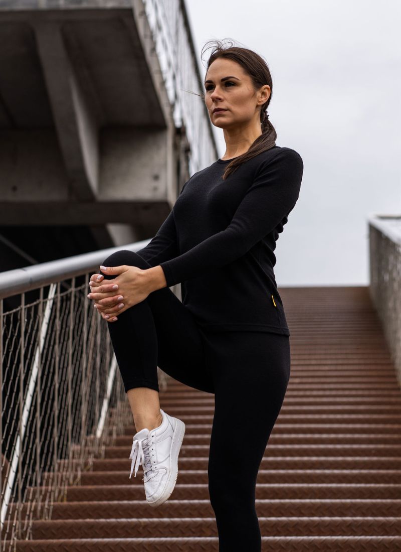 Woman in black athletic wear stretching on a staircase