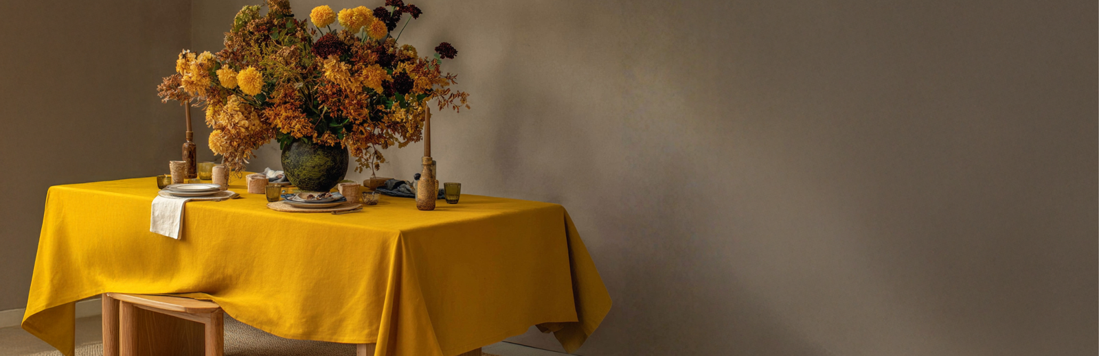 Linen tablecloth in mustard yellow on a dining table with autumn floral arrangement