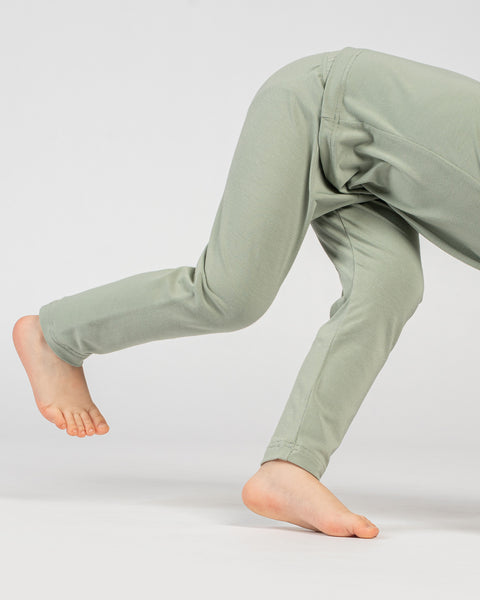 Close-up side view of child’s legs in green bamboo bottoms while playing.