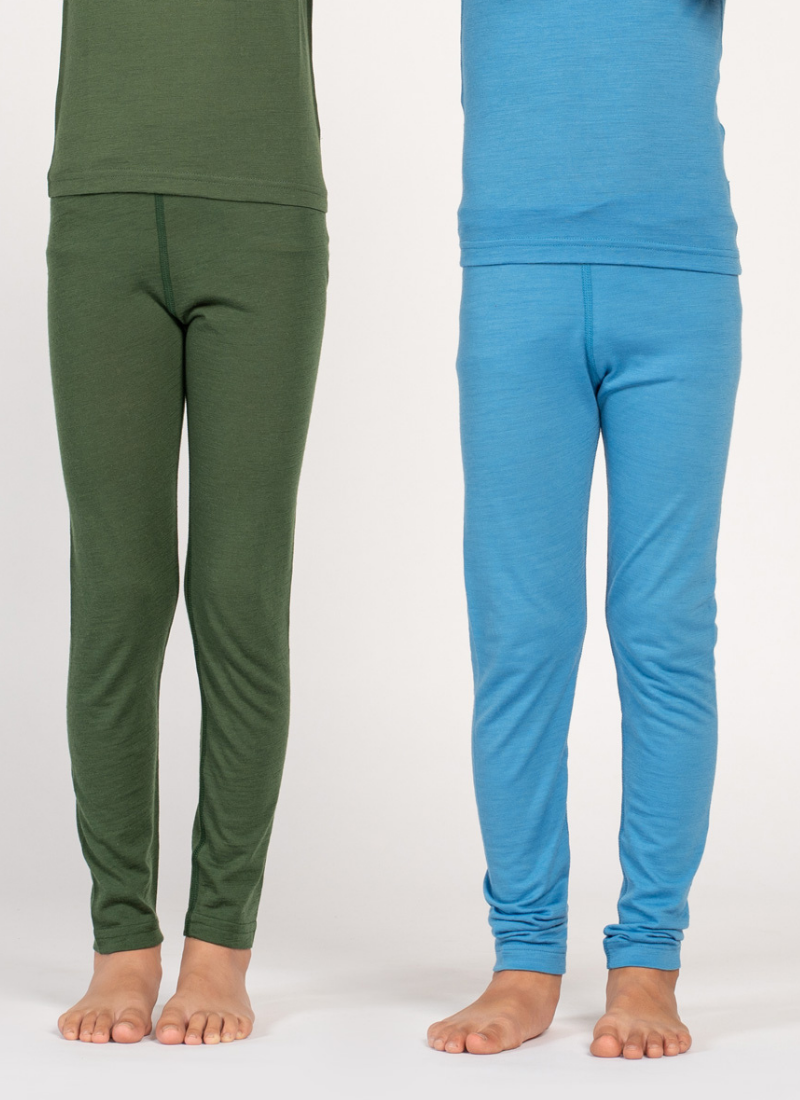 This cropped image shows the legs of two children standing side-by-side against a plain white background. One child is wearing dark green thermal leggings, while the other is wearing a light blue pair.