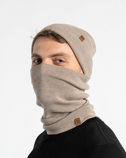 Man wearing a creamy beige merino wool knit beanie and neck gaiter set on a white background