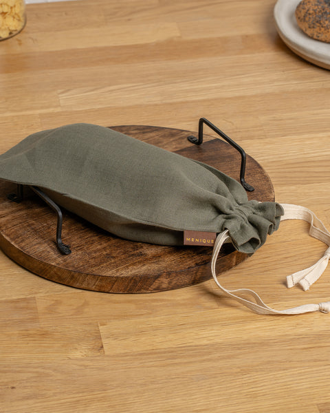Stone Green drawstring bag on a wooden surface with &#39;MENIQUE&#39; branding.