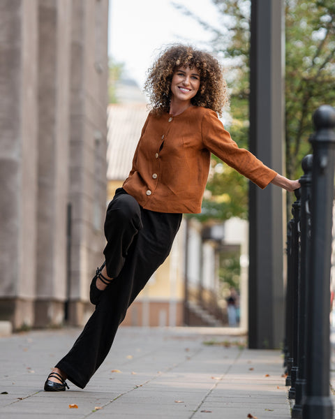 Woman with curly hair wearing almond brown linen jacket Alice and standing in  astreet