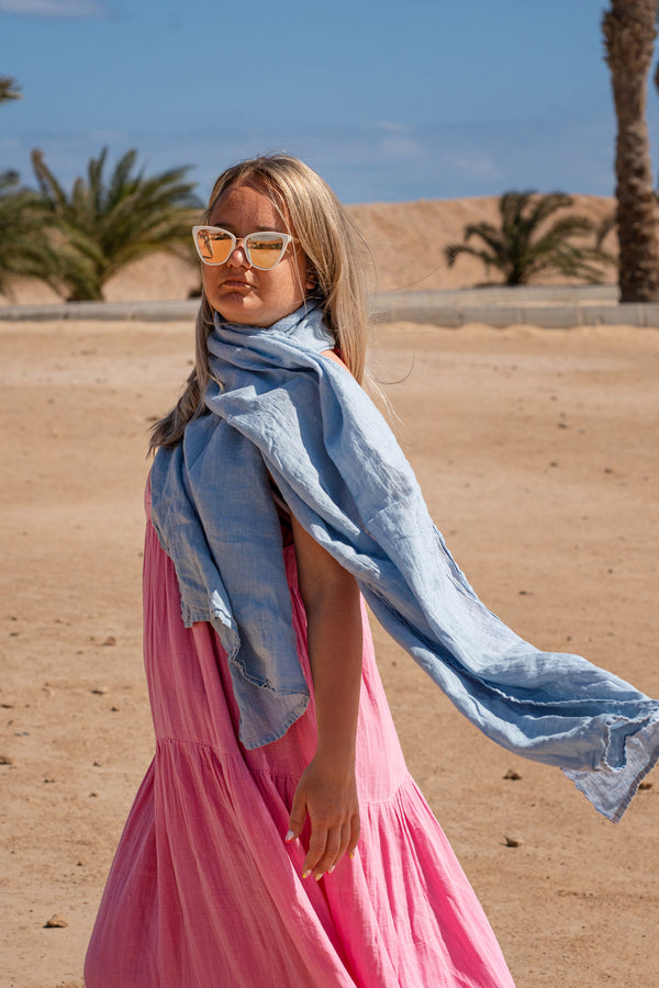 Women wearing Linen Scarf in Cloudy Blue color while in the background is seen palm trees