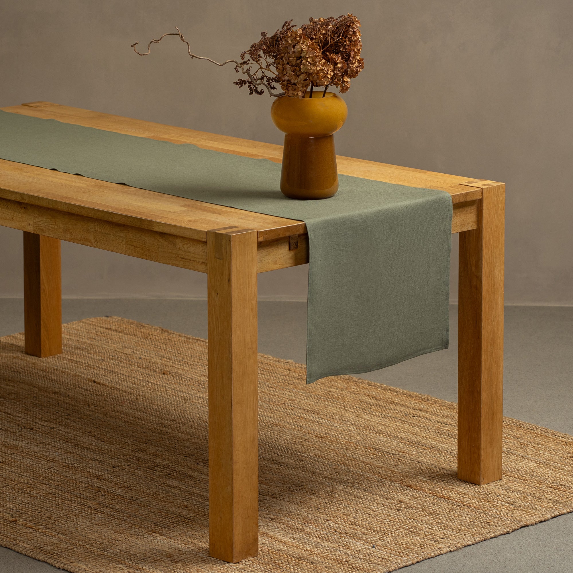 The menique spicy yellow color linen table runner on top of a wooden table. There is a vase on top of the runner.