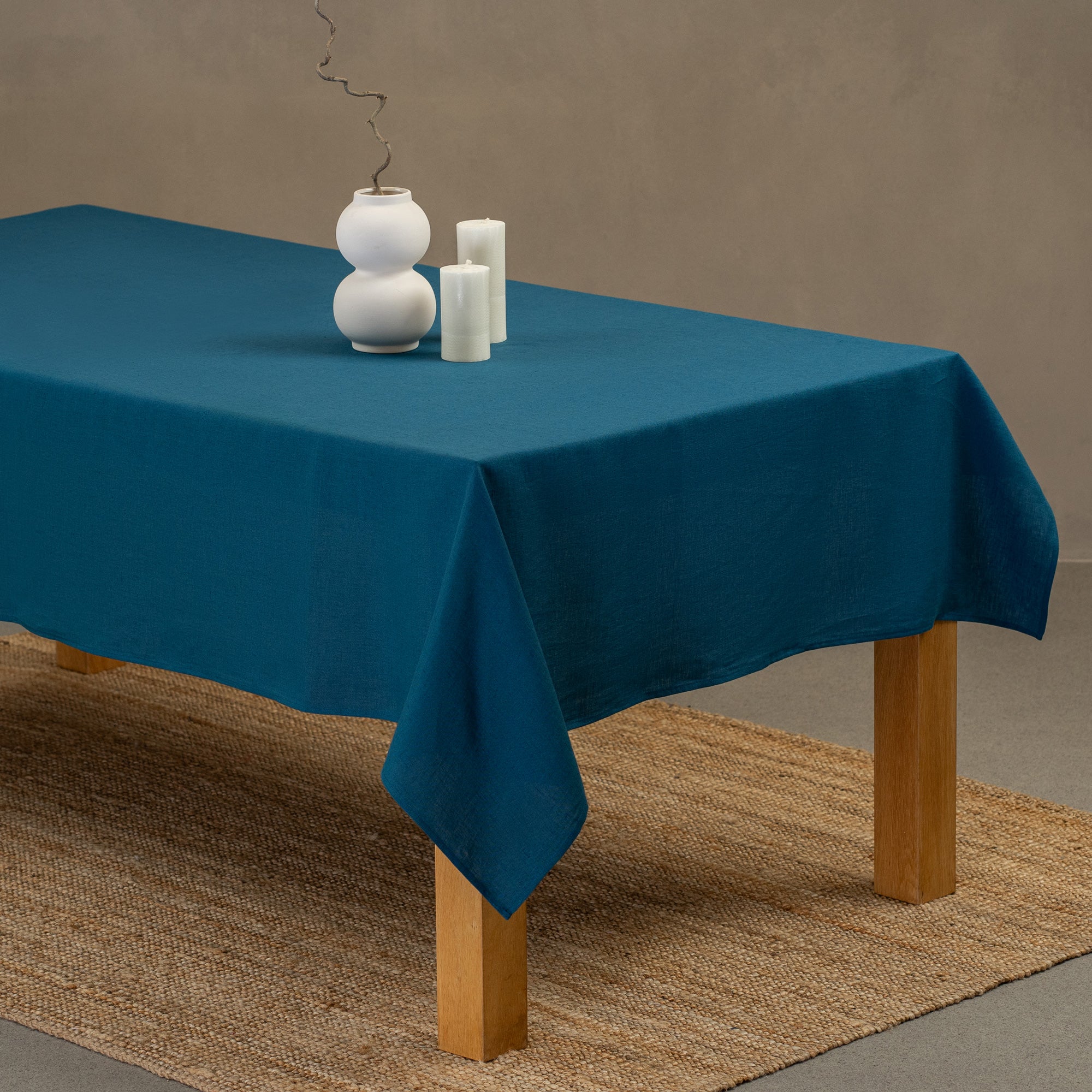 A cinnamon red linen tablecloth on a rustic autumn season wedding table. It has seasonal centerpieces on top and matching color linen napkins on top of the plates.