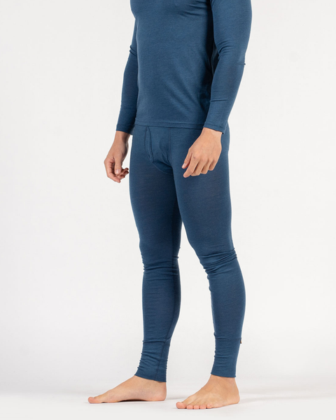 A person from the neck down standing barefoot against a white background, wearing a fitted, dark blue long-sleeved thermal top and matching thermal leggings with a front fly.
