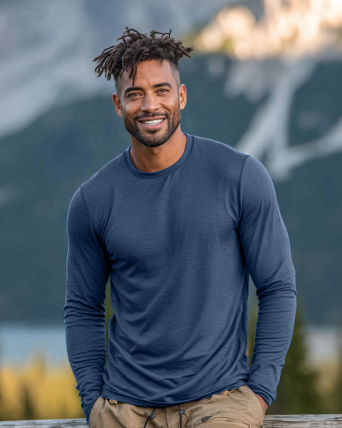 Man wearing a blue long-sleeve shirt standing in front of a mountainous landscape