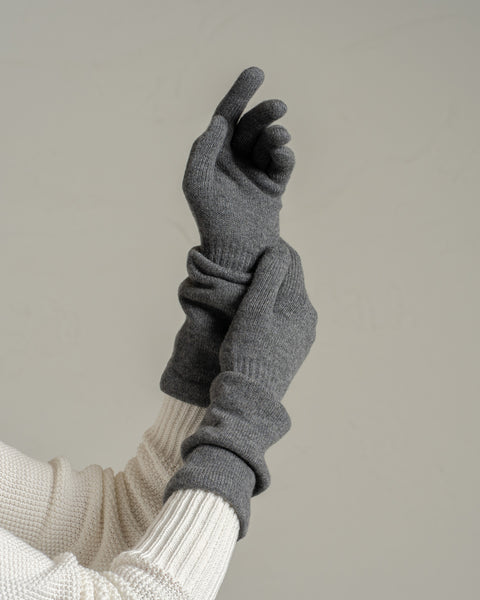 Close-up of dark gray merino wool knit long gloves worn on raised hand, emphasizing smooth knit structure and snug cuff.