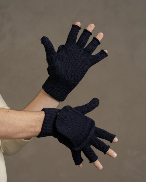 Dark blue merino wool convertible gloves worn on hands, featuring fingerless gloves with fold-over mitten flap for warmth.