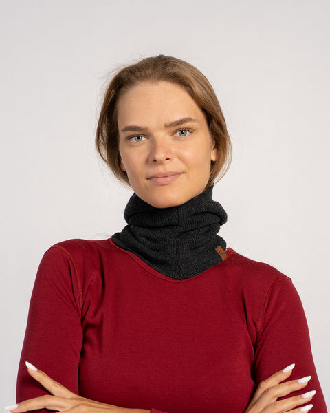 Woman in a red shirt wearing a dark gray knitted Merino wool balaclava styled as a neck warmer.