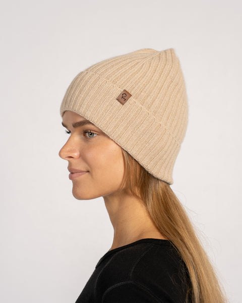 Unisex ribbed beanie in creamy beige, knitted from Merino wool and cashmere, shown in side view on a model with long hair.