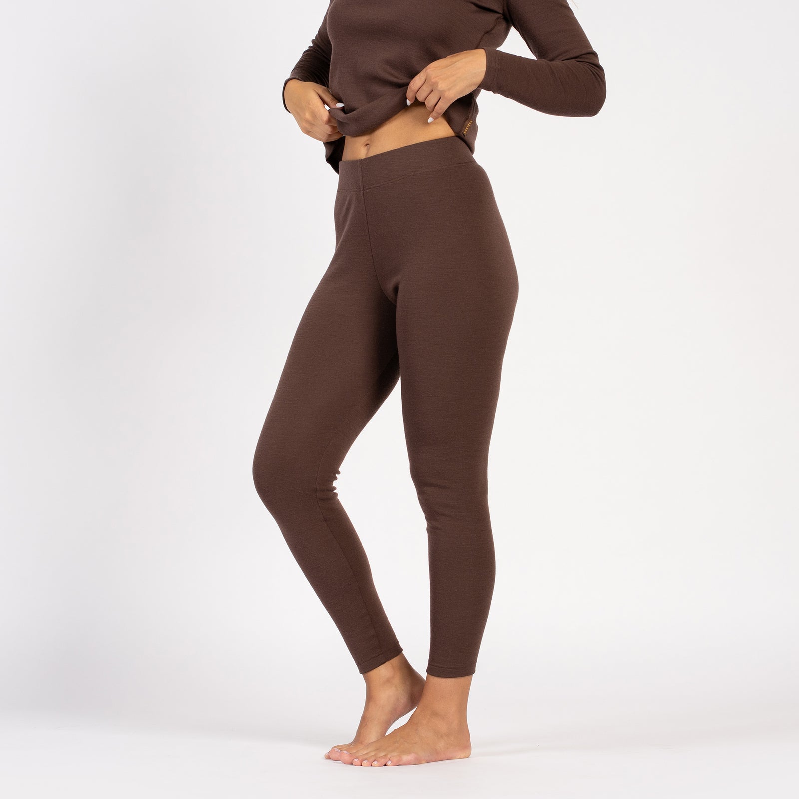 Side profile of woman in brown merino wool leggings and long-sleeve top.