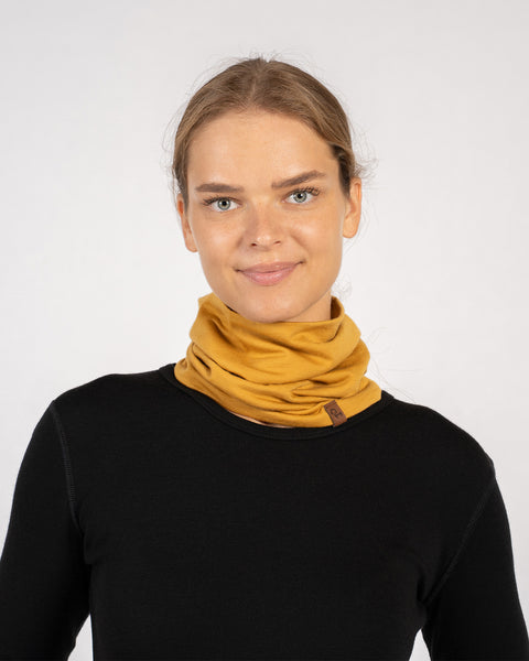 Front view portrait of woman smiling with yellow Merino wool gaiter on neck.