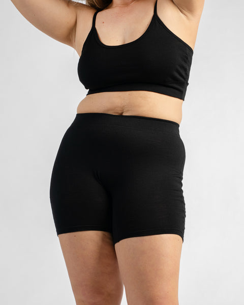 Front view of a model wearing a black sports bra with thin straps and black biker shorts.