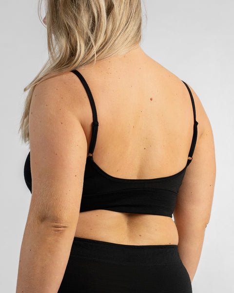 Back view of a model's torso wearing a black sports bra with thin straps and black bottoms.
