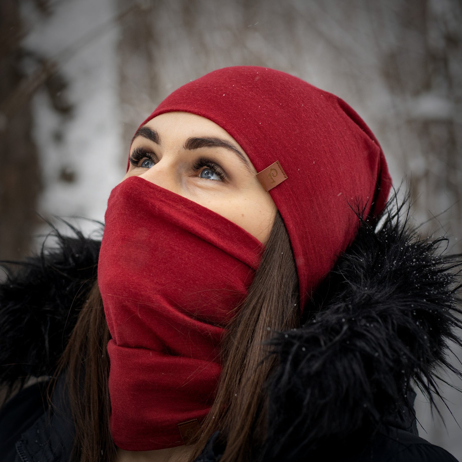 Person wearing a red beanie and face mask against a blurred background
