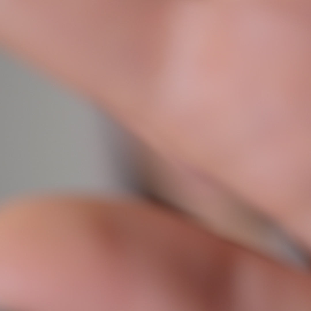 Model wearing merino wool knit oversized bandana, turning slightly and looking to the side in a studio setting.