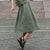 Woman with a curly hairstyle posing in a city, wearing stone green crop top and stone green skirt Sophia.