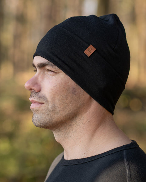 A man, standing outside during fall season, wearing the menique Men&#39;s Merino Beanie Hat in Black Color.